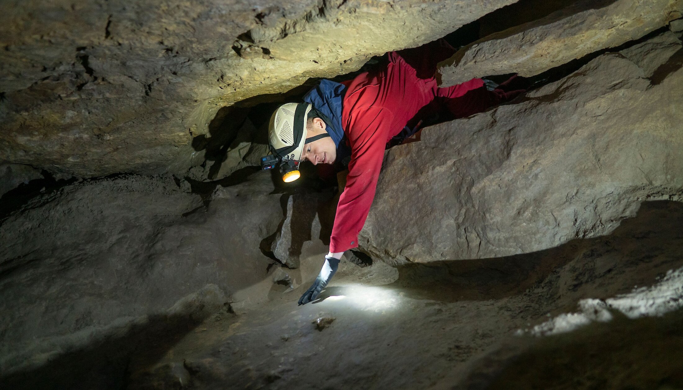 A man squeezing through a rock in a cave in Canmore