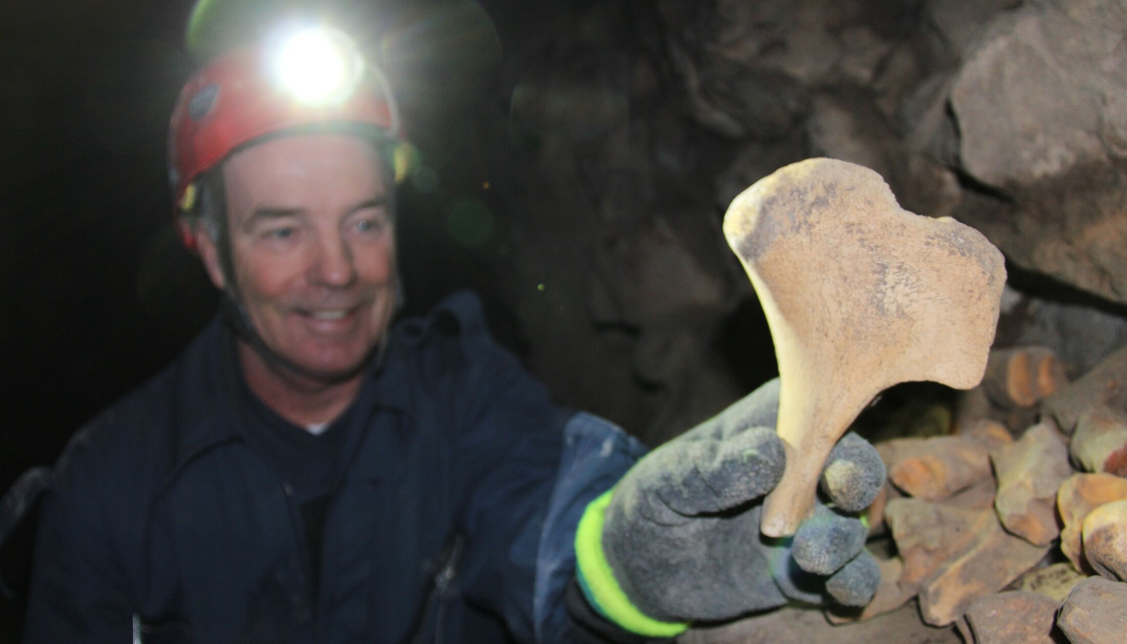 A man showing a rock formation on a tour in a cave in Canmore