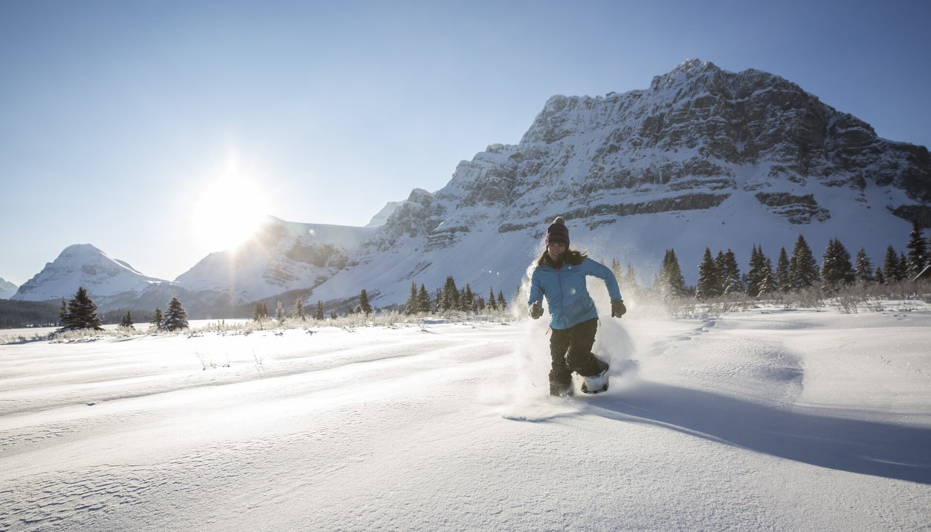 A woman running through deep snow a frozen lake in Banff National Park