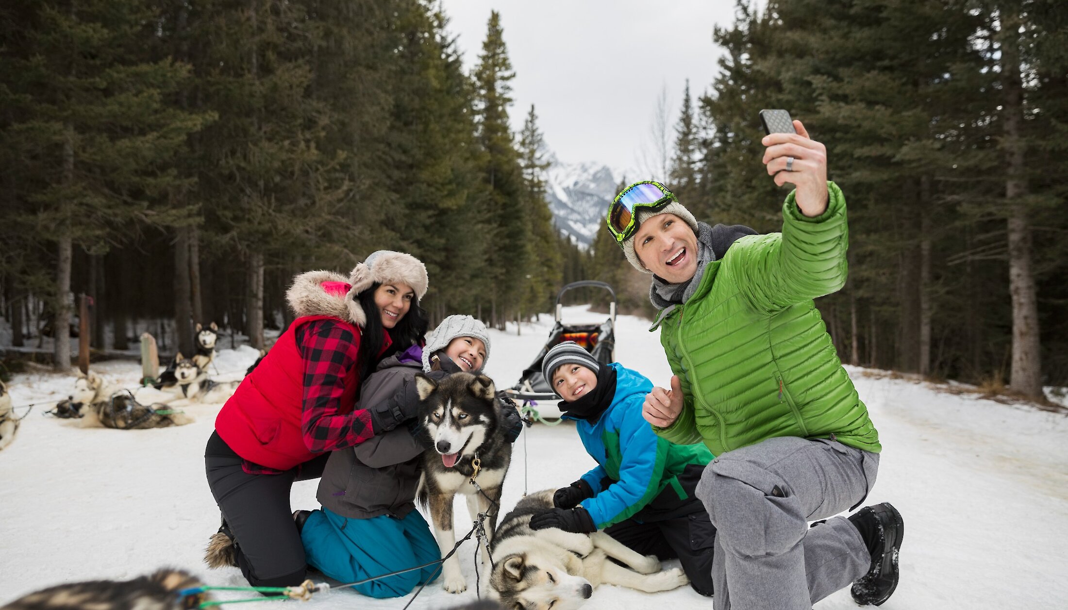 A family taking a photo with the dog sled dogs on Spray Lakes