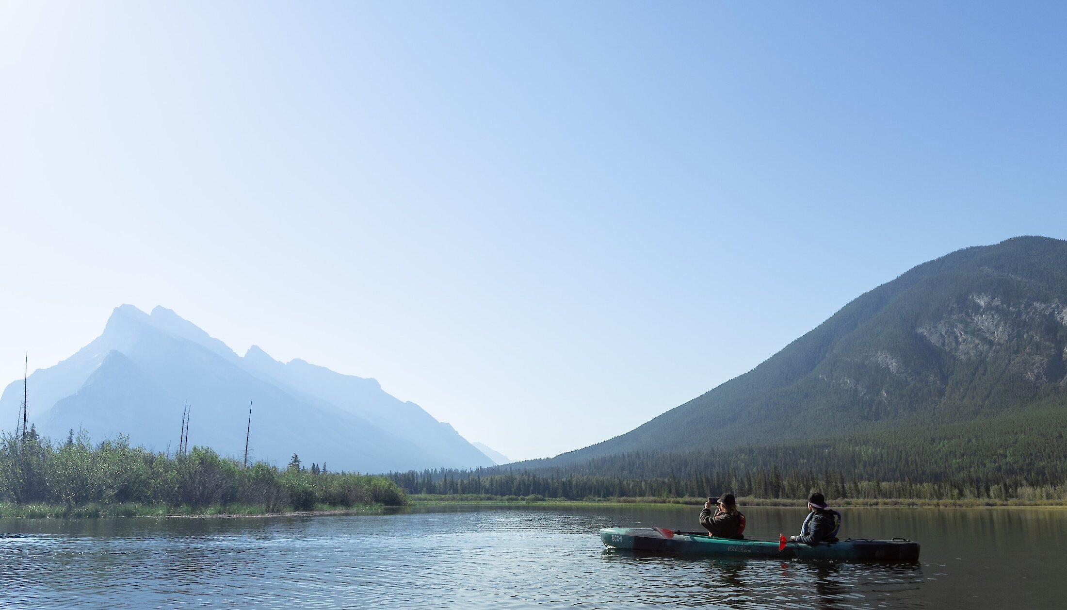 A double kayak in taking a photo of Mount Rundle
