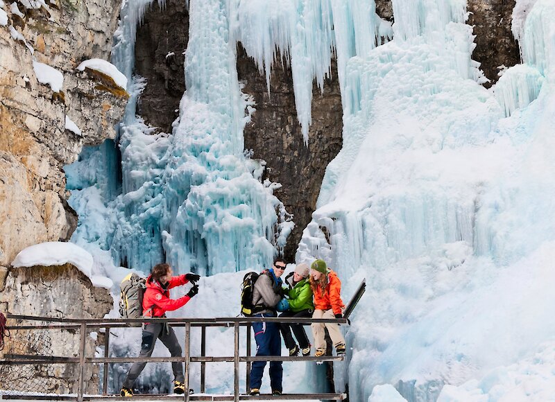 A group taking photos in front of the Johnston Canyon frozen waterfall in Banff