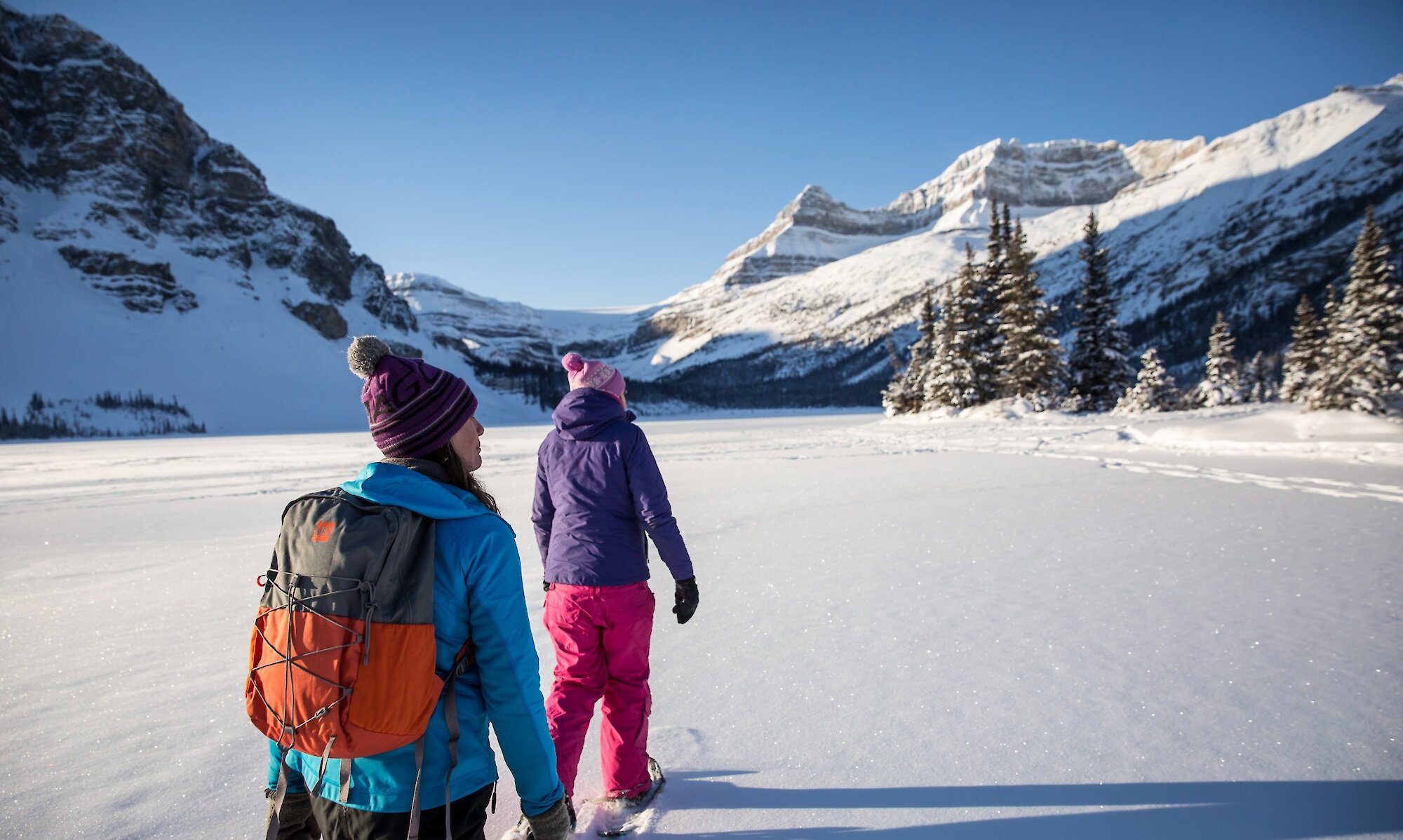 Friends snowshoeing on a frozen lake on the Icefields Parkway in Banff