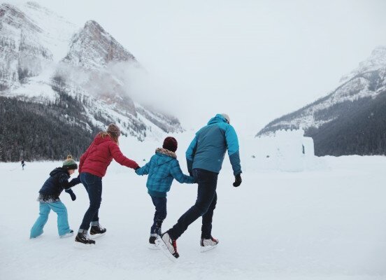 A family ice skating at Lake Louise on the frozen lake