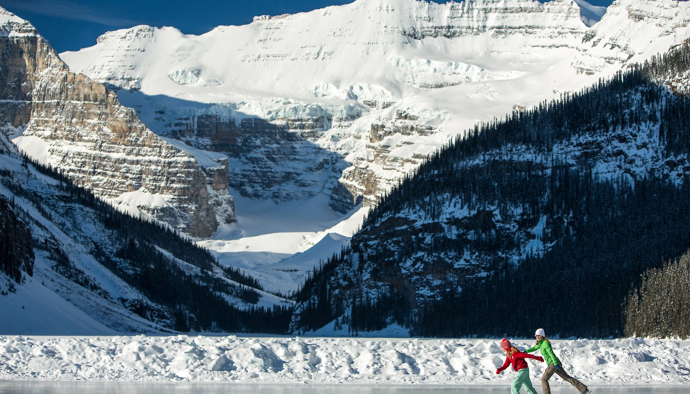 A mother and daughter ice skating on Lake Louise in winter