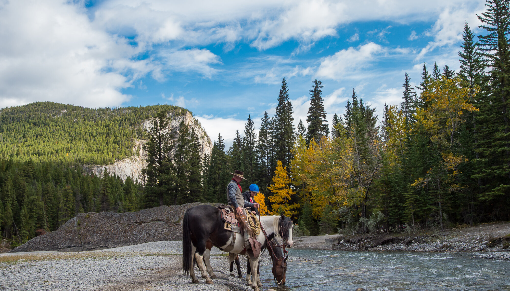 Horseback rides crossing the Spray River in Banff
