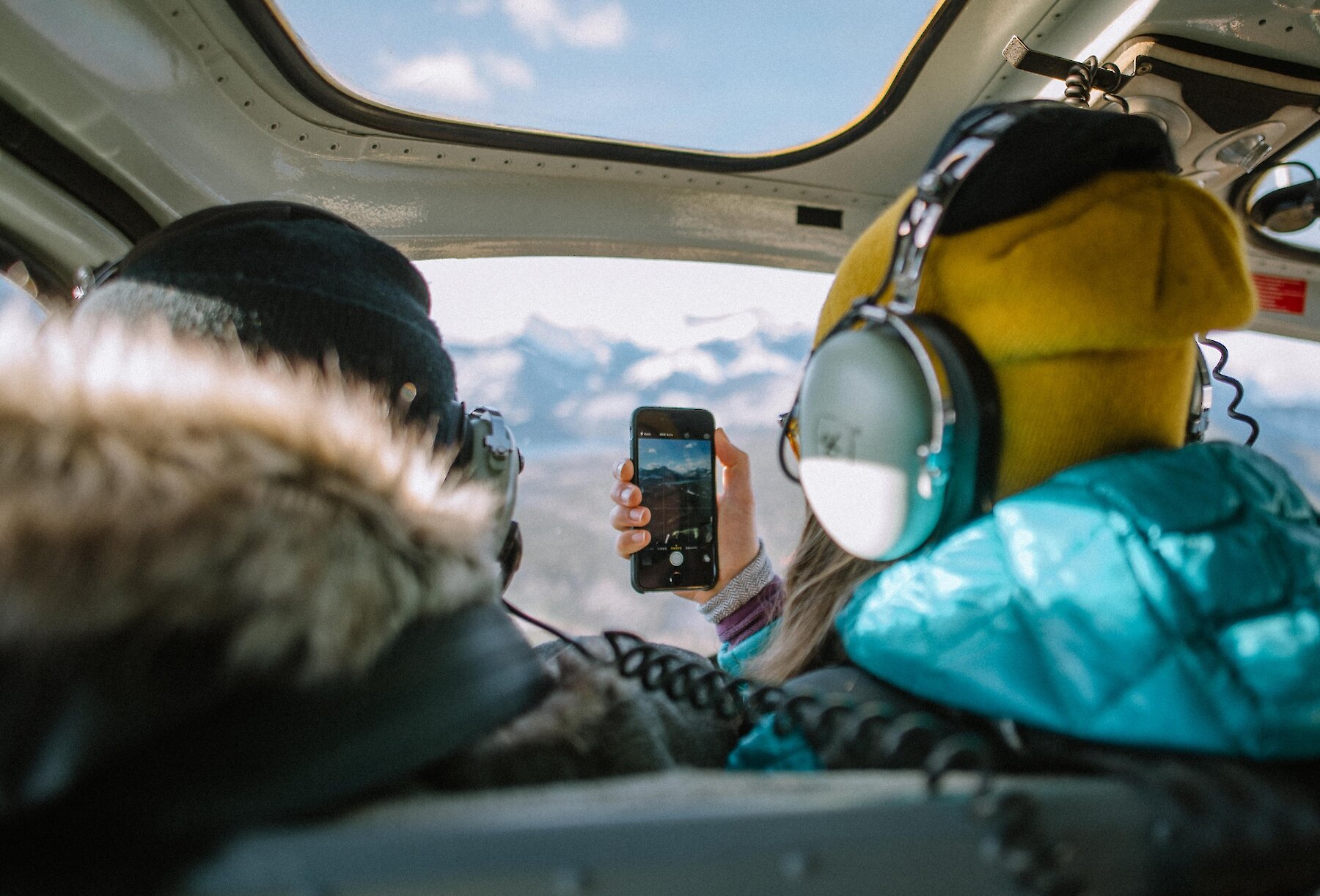 A couple taking photos during a winter helicopter flight