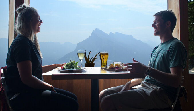 A couple enjoying some food and drinks at the Cliff House Bistro at the top of the Mount Norquay Chairlift