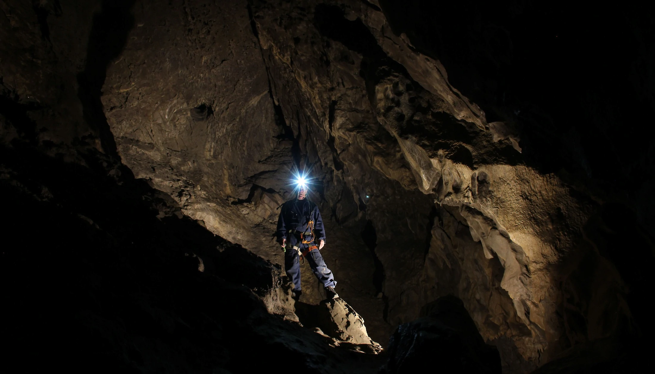 A person with a headlamp on a cave tour in Canmore
