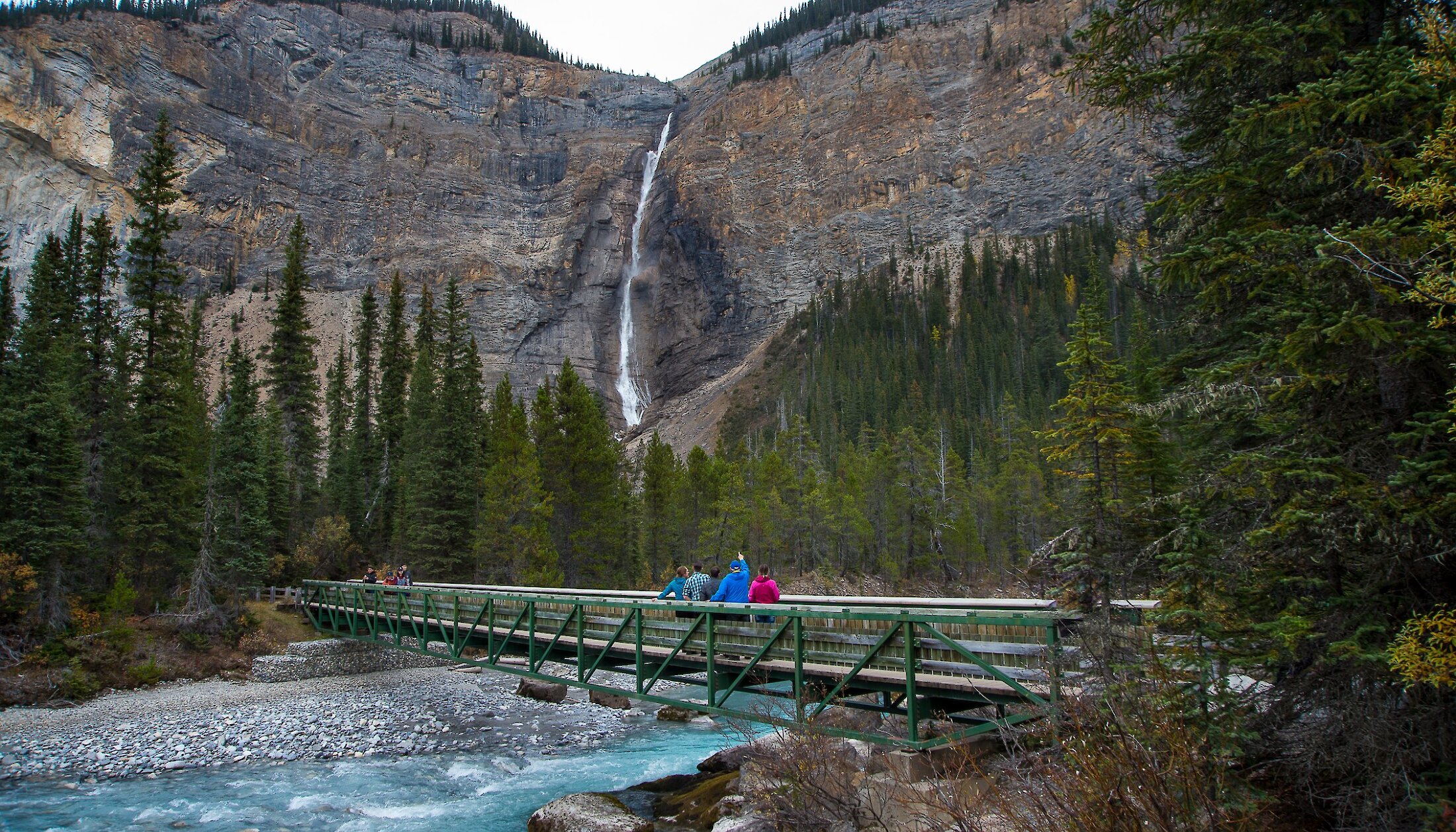 people walking over a bridge at Takakkaw Falls