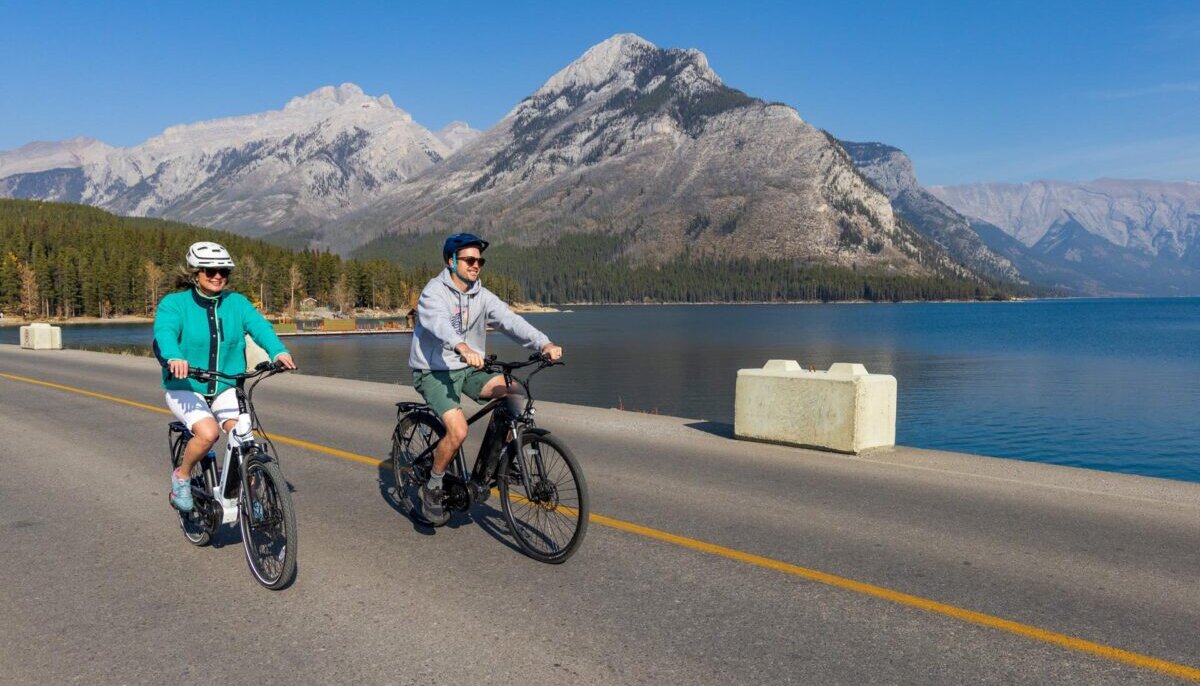 A couple cycling next to Lake Minnewanka in Banff