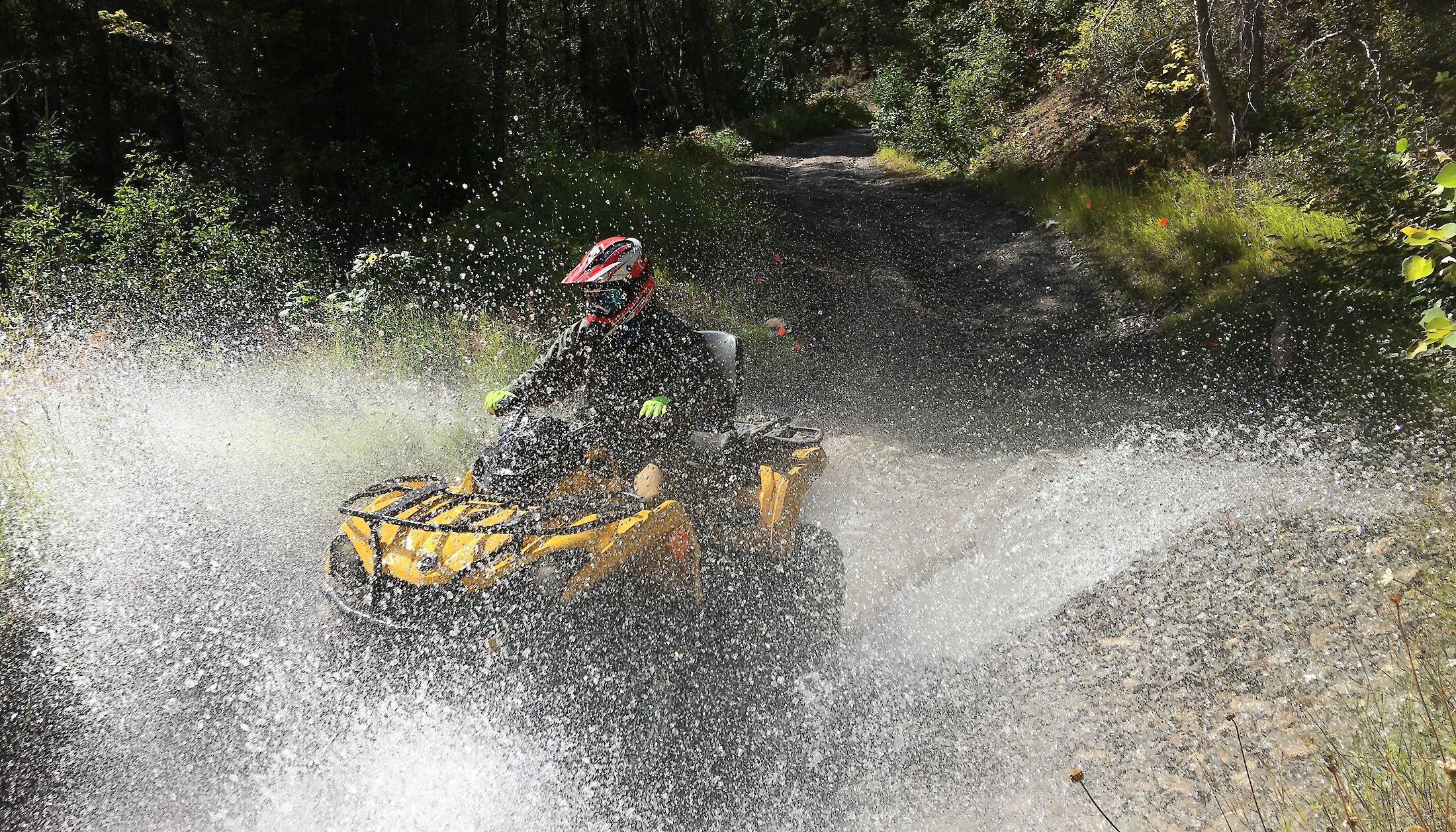 An ATV splashing through a large puddle of water in Golden