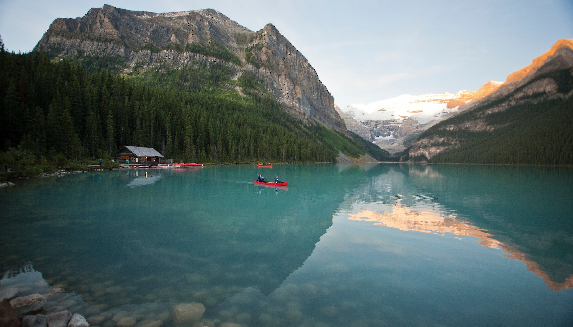 A canoe on Lake Louise as the sun rises over the Victoria Glacier in Banff National Park