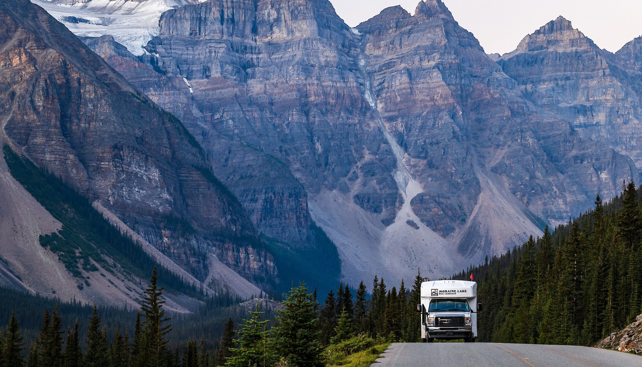 A shuttle driving Moraine Lake bus road with the Valley of 10 peaks in the background