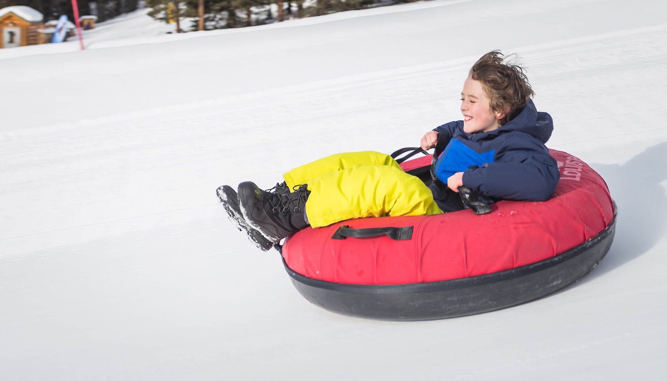 A young child going fast whilst snow tubing at Lake Louise