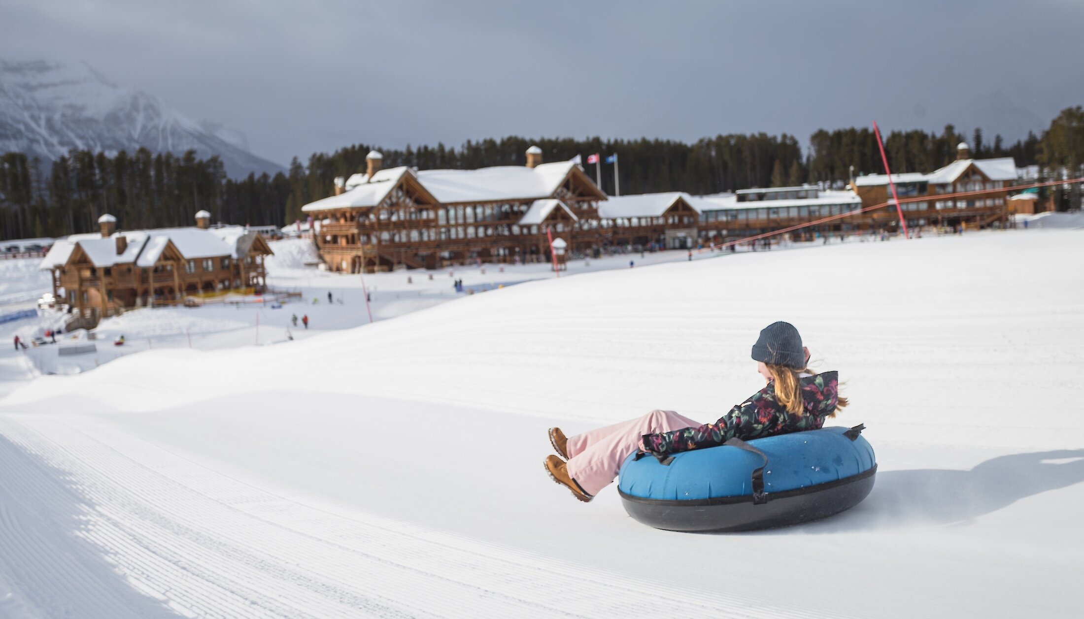 Snow tubing with the view of the Whiskey Jack Lodge at Lake Louise Ski Resort