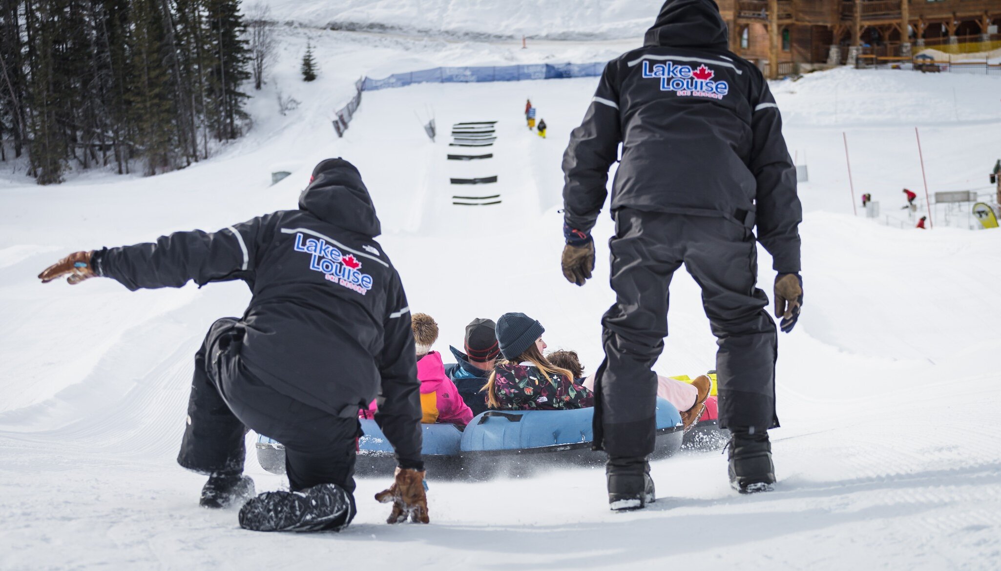 Family being pushed down the tubing lane by Lake Louise Tube Park