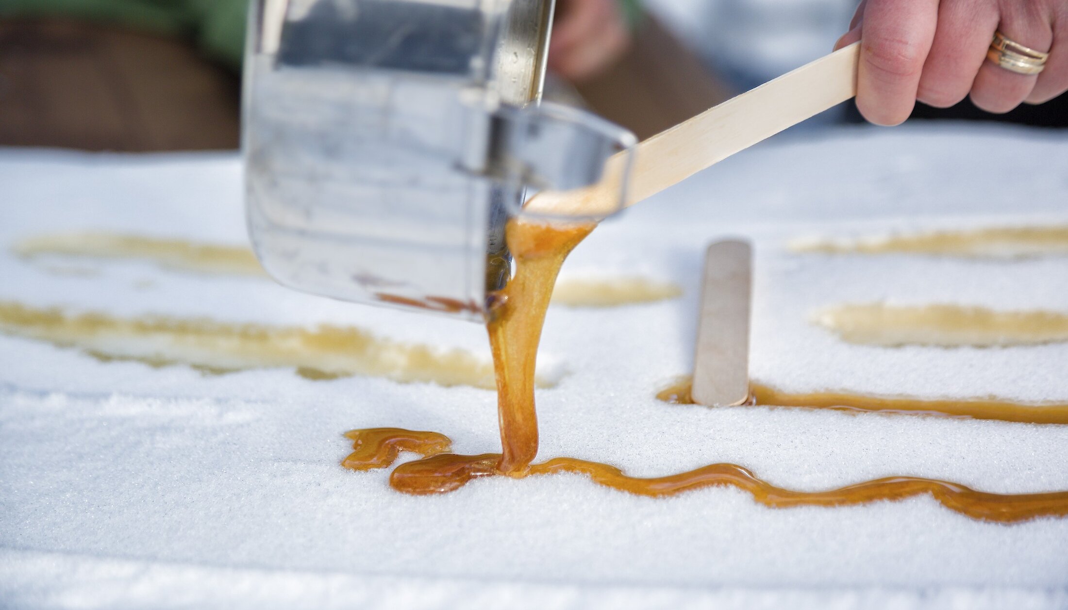 Pouring maple taffy into the snow on a snowshoe tour