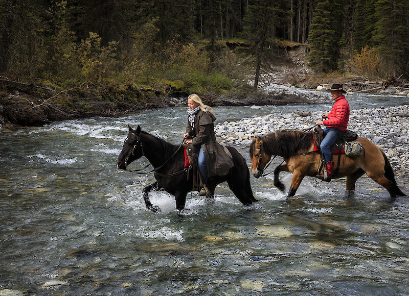 2 Horsback riders crossing the river in Banff National Park