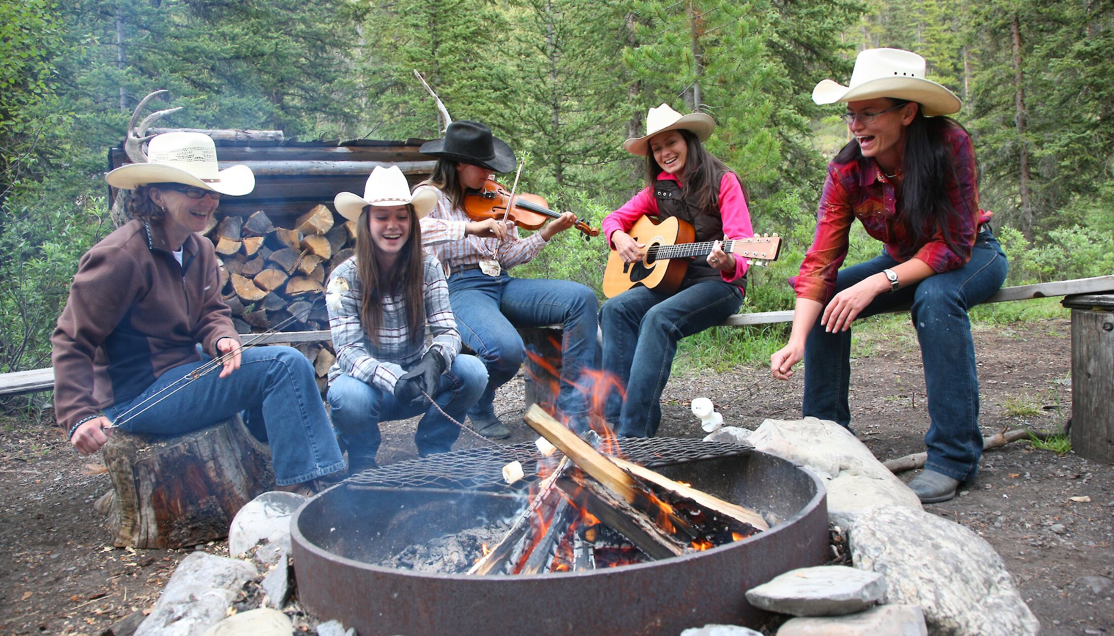 A group enjoying some S'mores and music by an outdoor fire in Banff Sundance Lodge