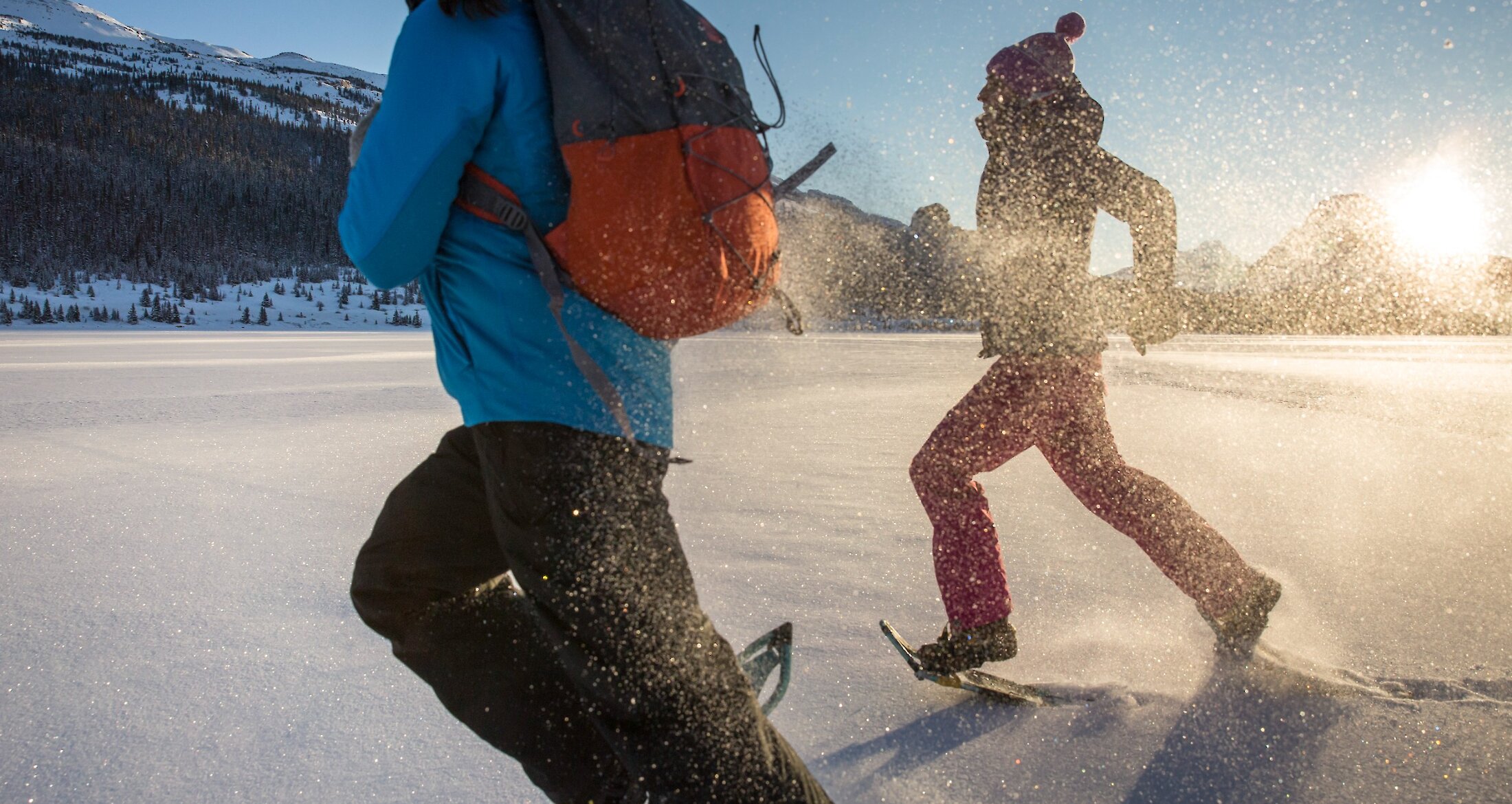 2 people running in snowshoes in snow on the bow lake