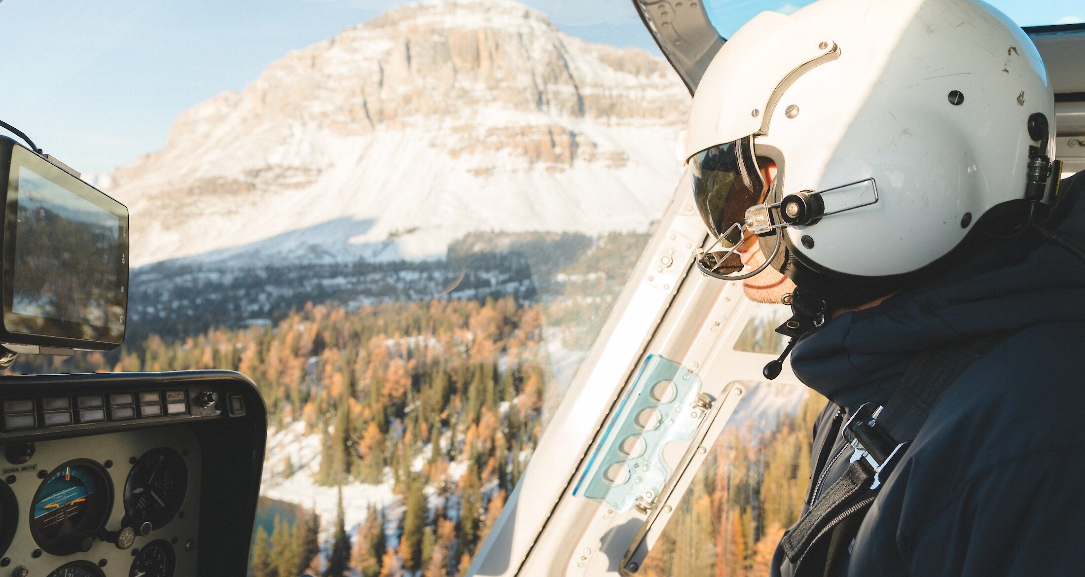 A pilot flying a helicopter in winter overlooking the mountains