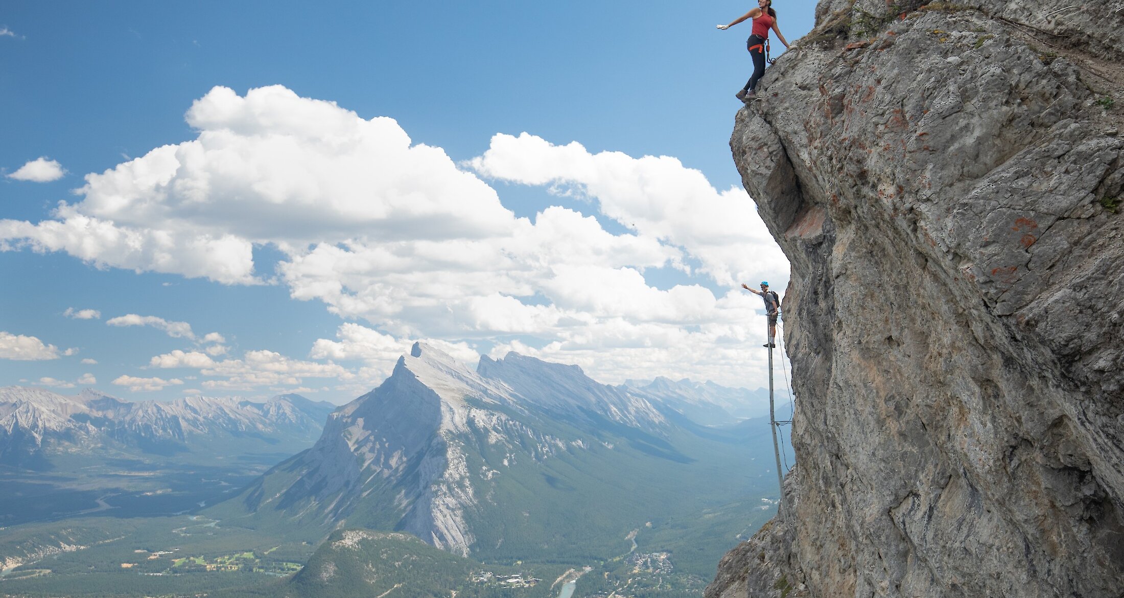 A couple climbing a ladder at Mount Norquay's Via Ferrata