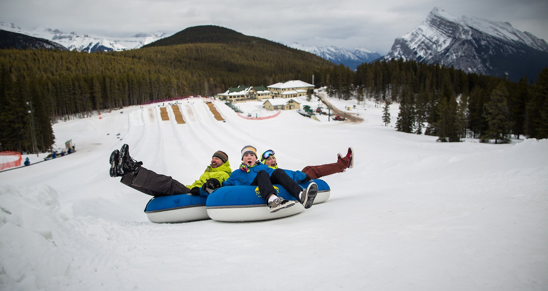 3 people heading down the tube lane at Mt Norquay in Banff