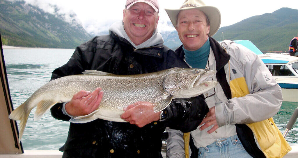 Two people with a fresh fish caught on the Lake Minnewanka Fishing Tour