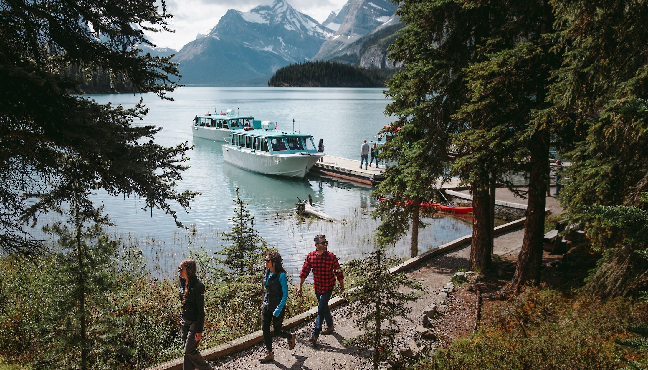 A group of friends walk the shoreline of Maligne Lake at Spirit Island