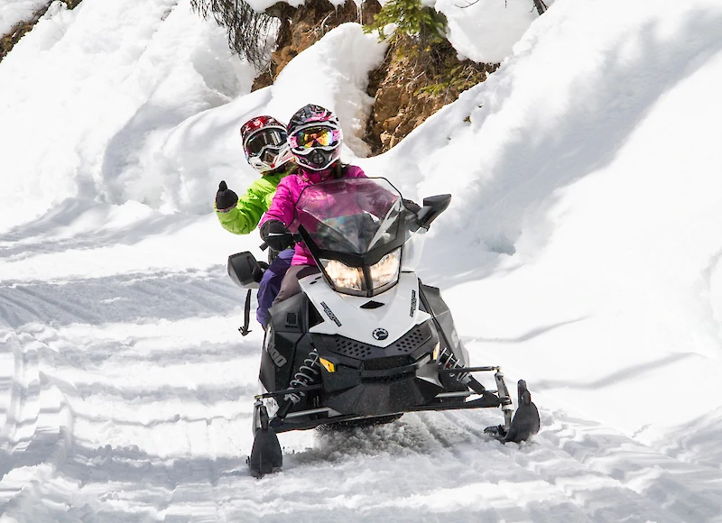 A snowmobiling riding through the snow covered trees