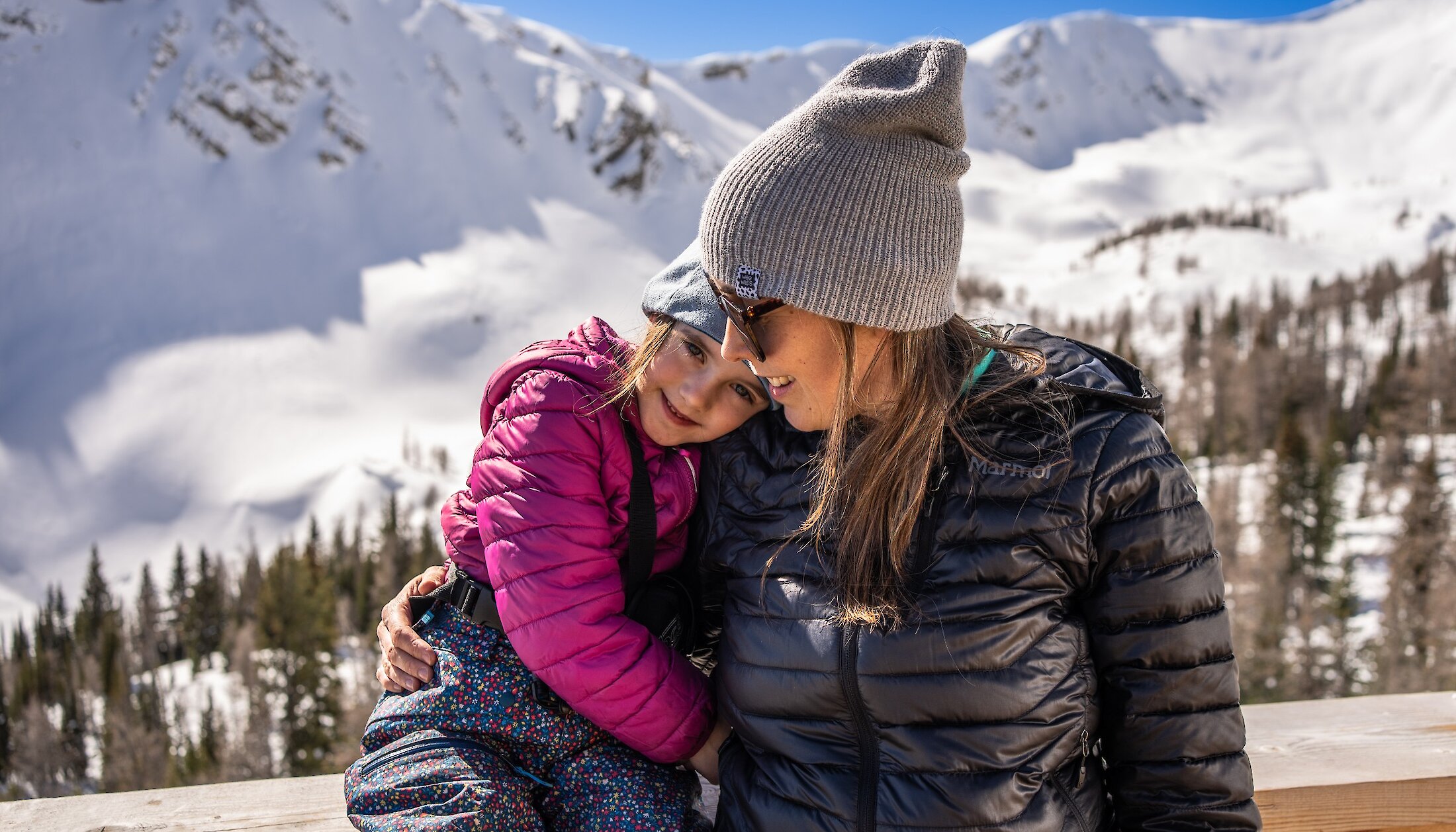 A mother and daughter hugging at the cabin on a snowmobile tour