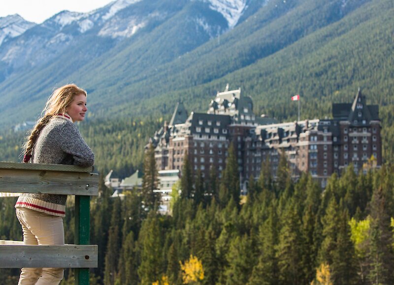 A woman looking at the Fairmont Banff Springs from the Surprise Corner viewpoint