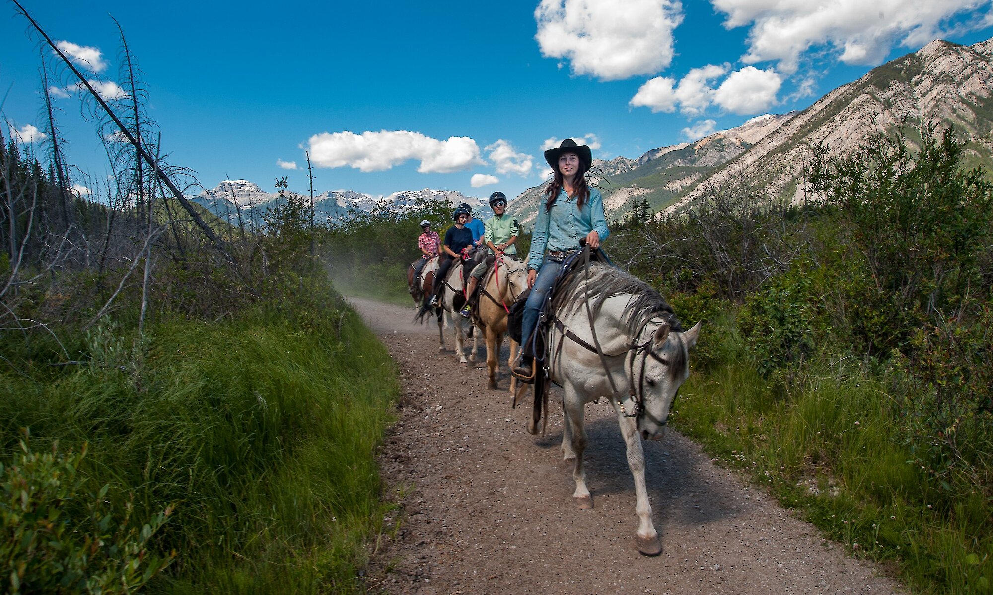 A group of horseback riders on the the bow river trail with a friendly guide