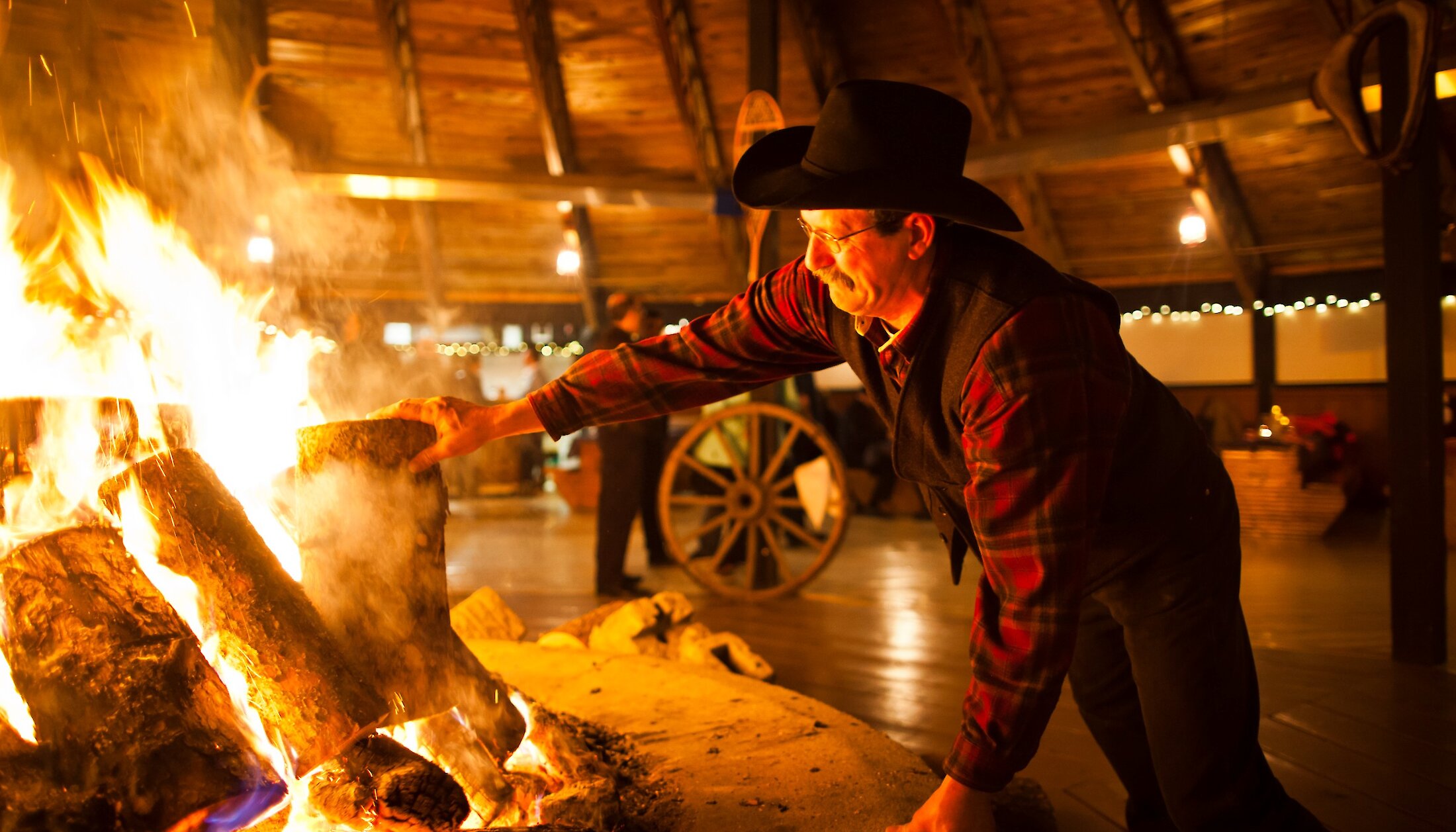 A cowboy stoking the campfire in the Roundhouse at Banff Park Ranch