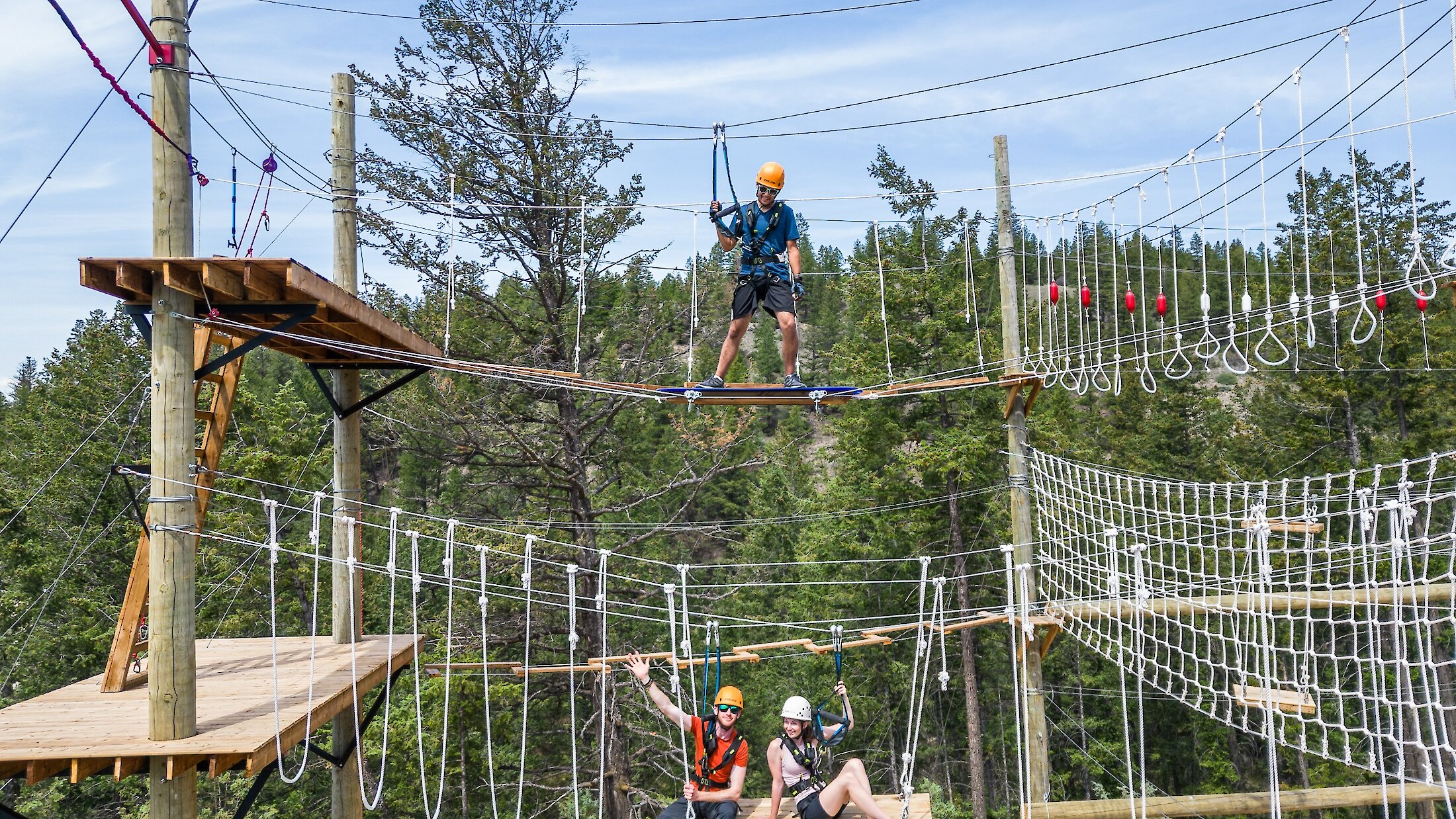 Three people on different obstacles on the aerial course.