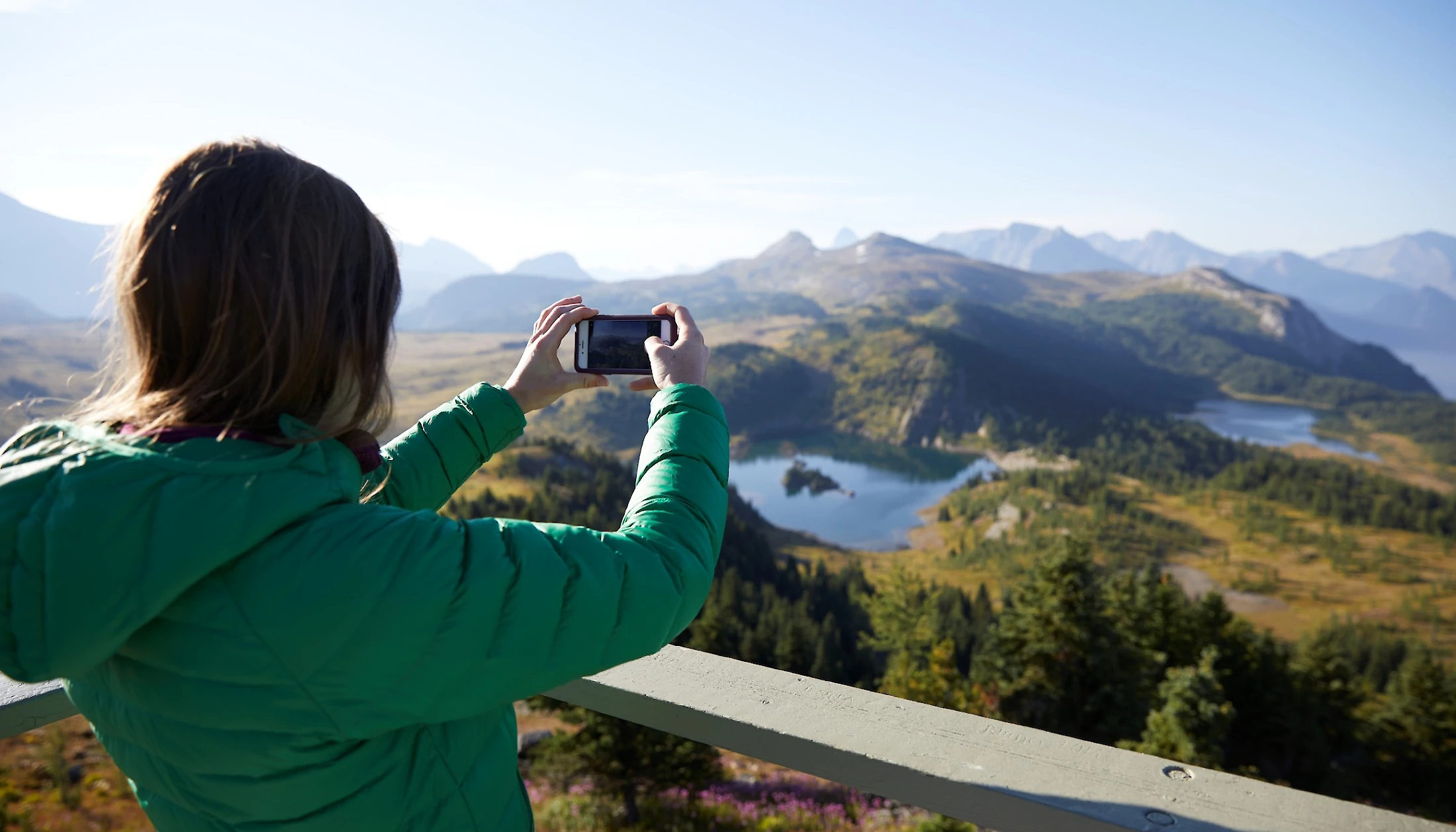 A woman taking a picture of the Sunshine Meadows Lakes from the Standish Viewpoint
