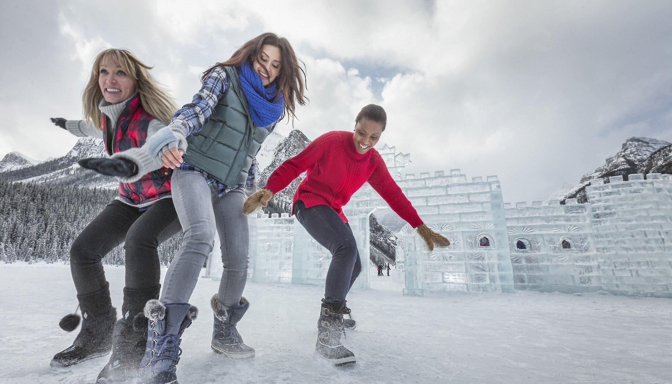 Three friends standing in front of the Ice Castle on Lake Louise