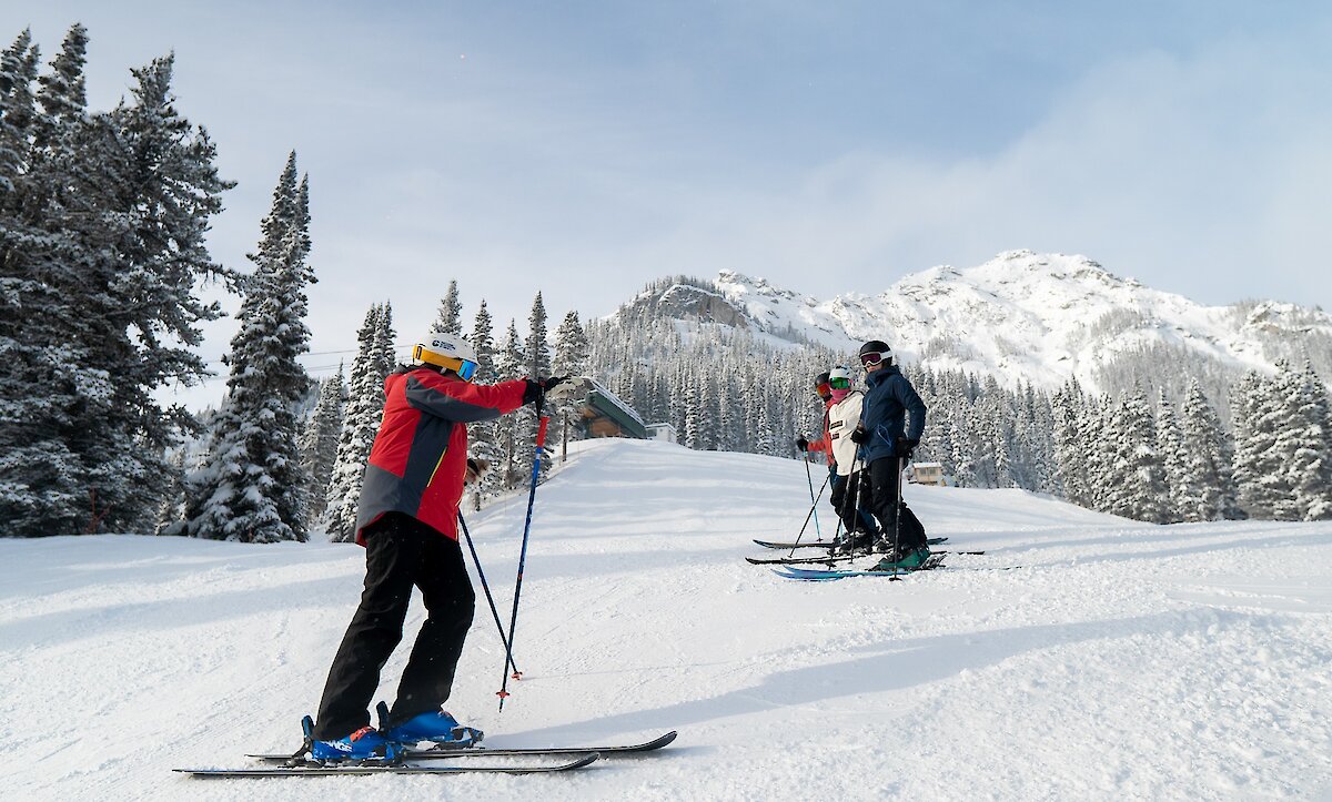 A ski Instructor providing advice to a group of adults in a ski lesson