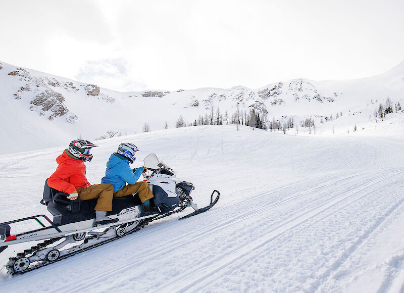 Two friends enjoying the powder on the snowmobile tour at Paradise Basin
