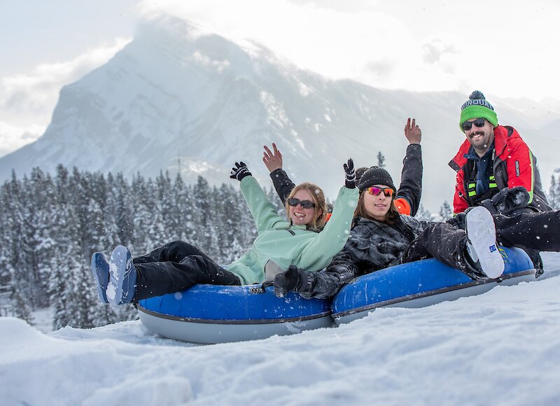 A group of friends snow tubing at Mount Norquay before being pushed down the lanes.