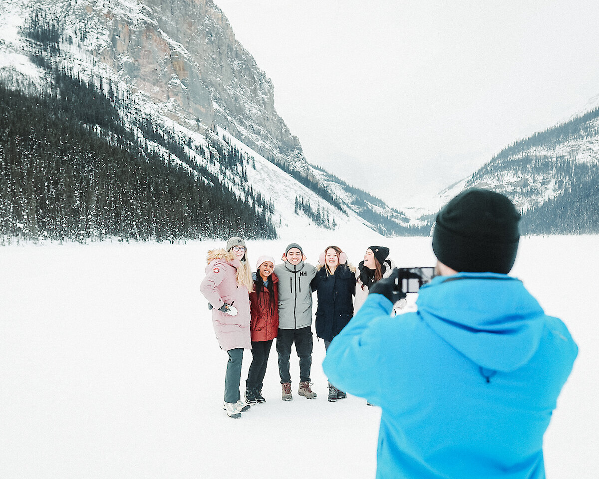 A guide taking a picture of a group of friends on Lake Louise