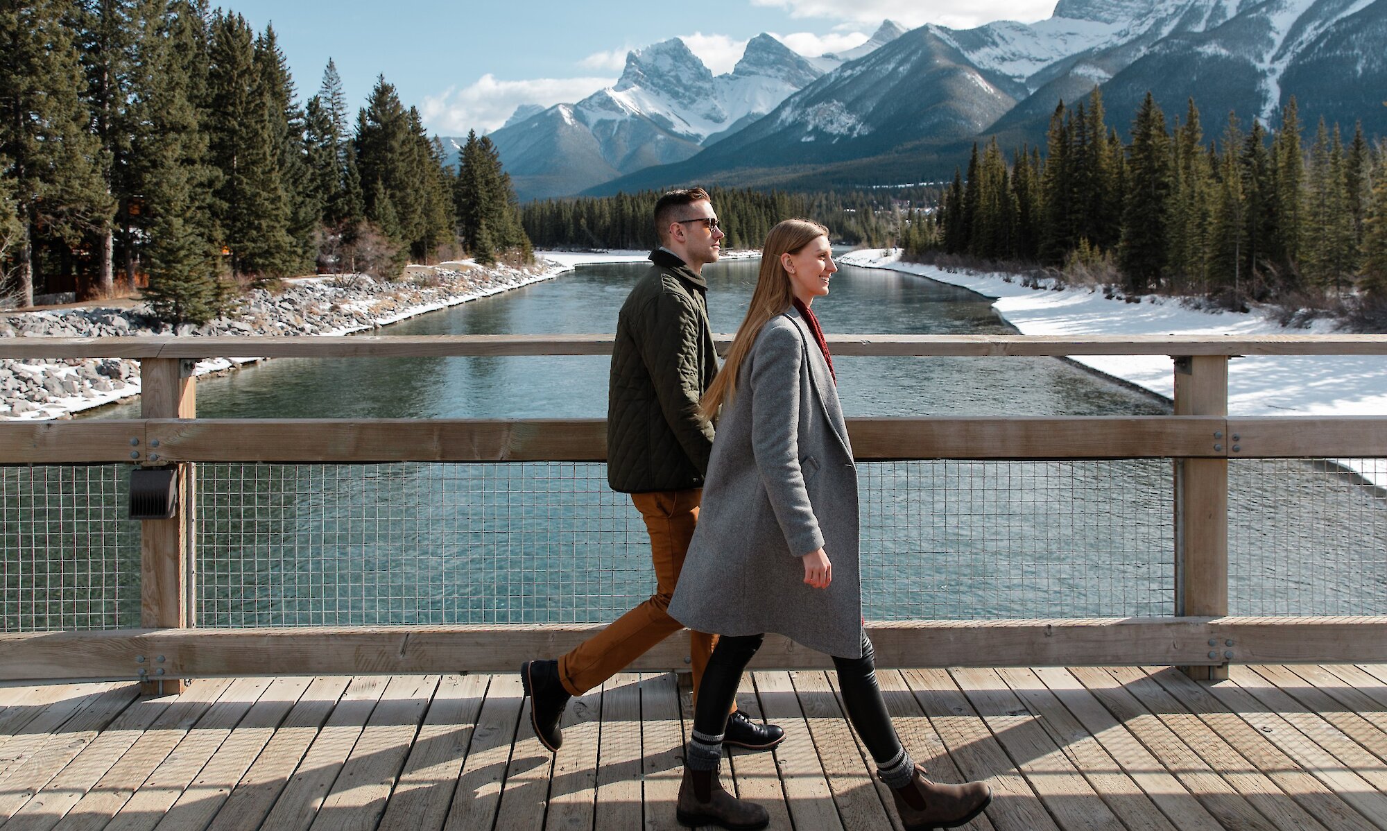 A couple walking across the pedestrian bridge in Canmore