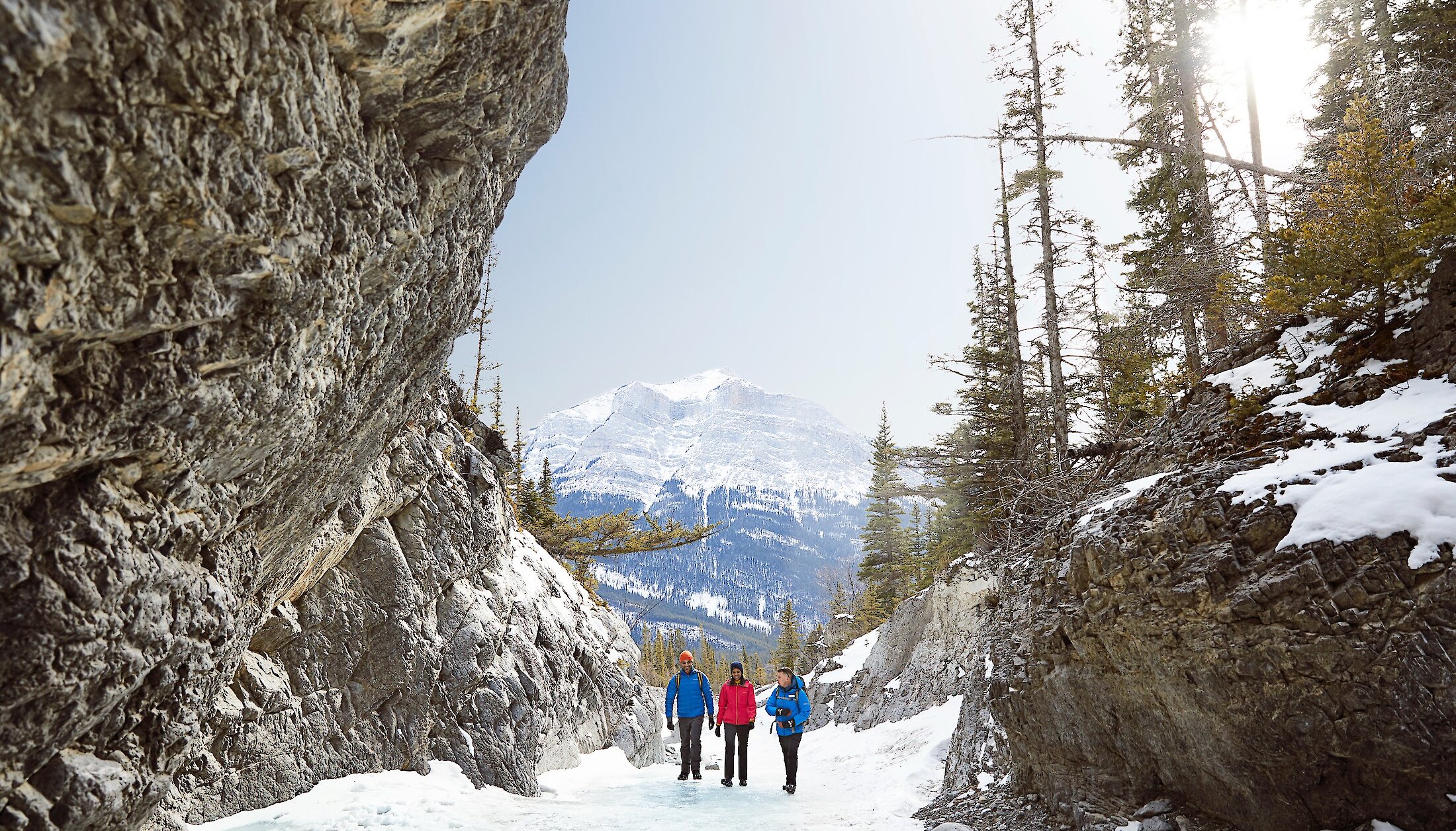 A guide and a couple walking along the frozen riverbed of Grotto Canyon