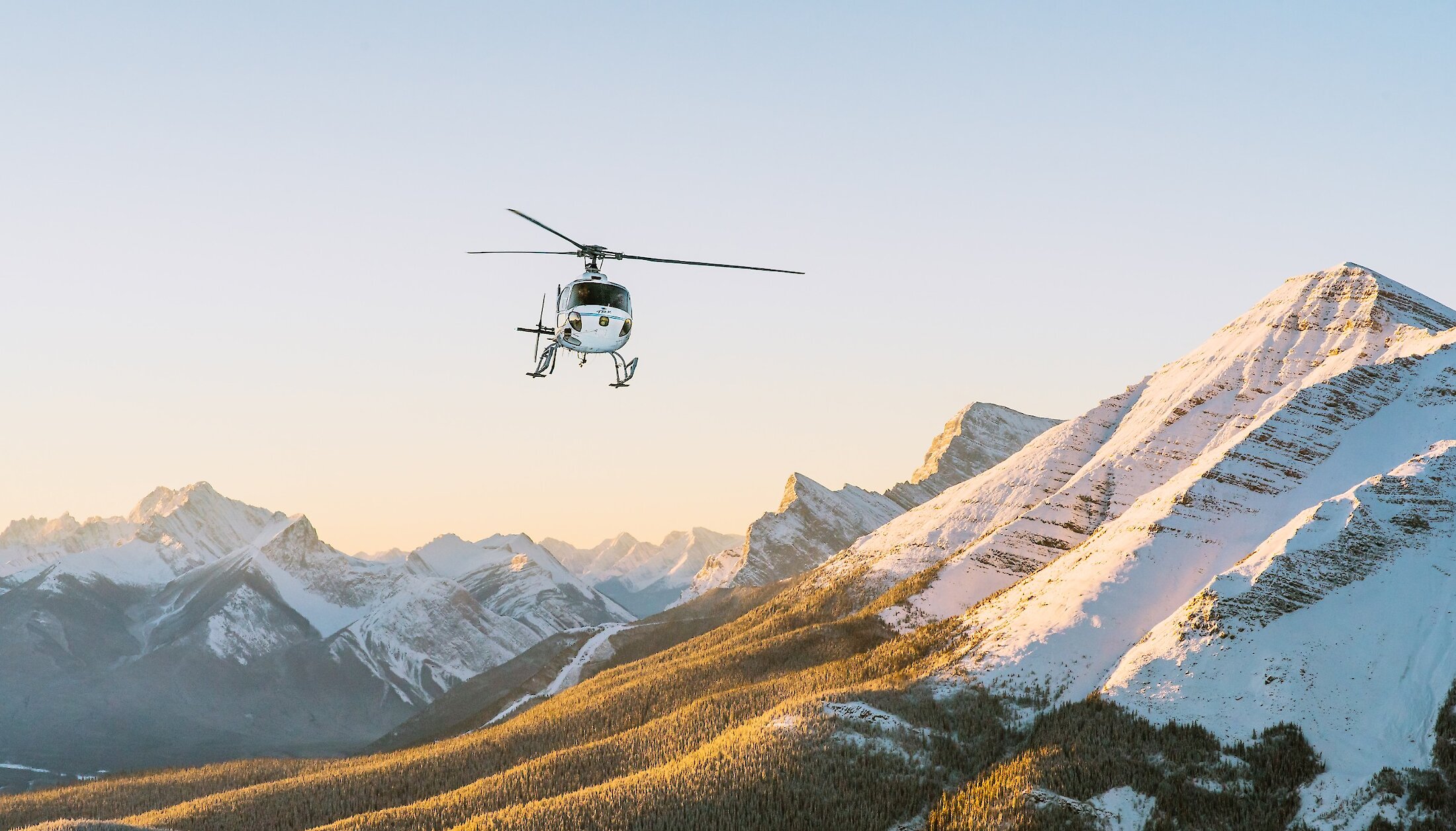 A helicopter flying over the Canadian Rockies from Canmore