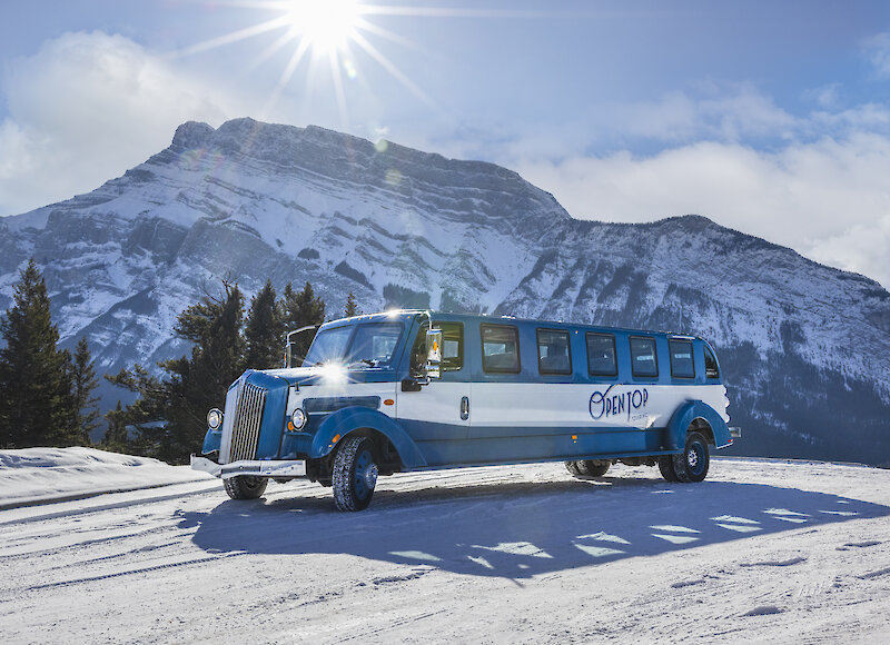 A view of the open top tour bus with Rundle Mountain in Banff National Park