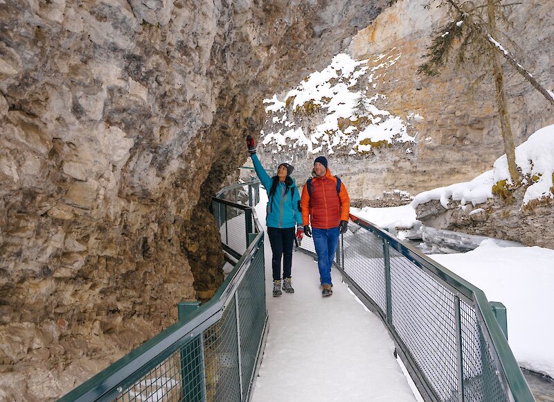 Couple walking on the frozen catwalk in Johnston Canyon