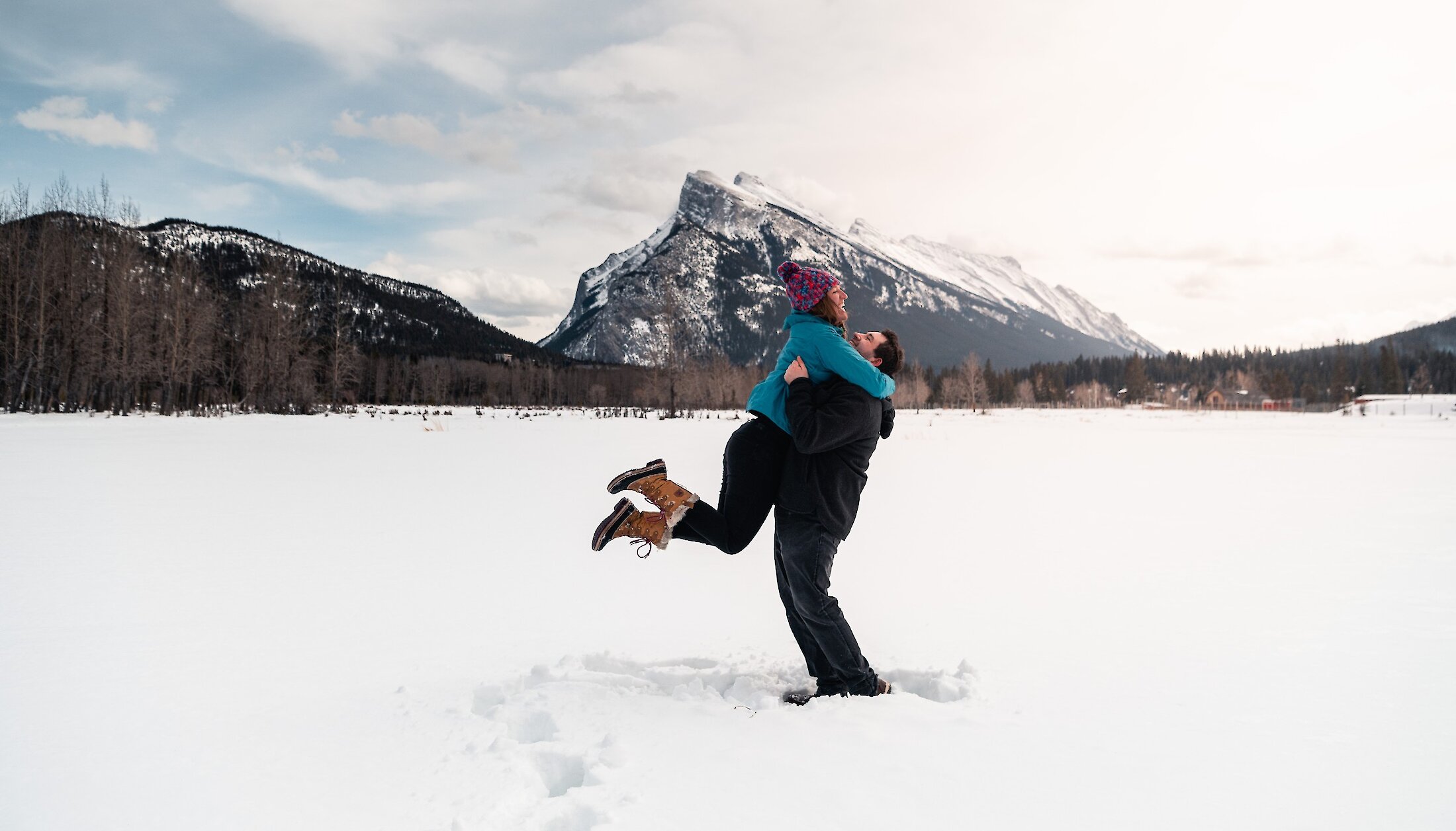 A couple celebrating with the snow after a proposal