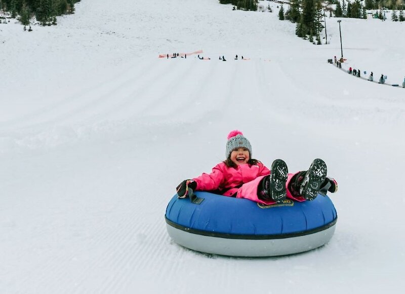 young girl laughing during a snow tubing adventure