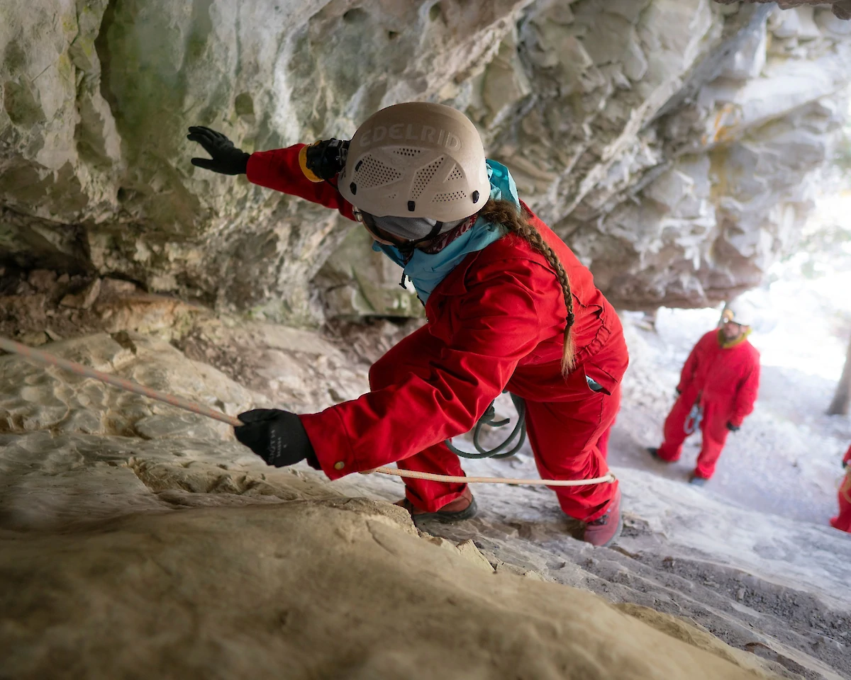 Climbing up to the cave entrance using a rope